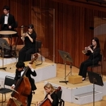 透明なアクリル板を設置したり、隣との距離を空けて座ったりして感染予防をしながら演奏する団員ら＝１９日午後、西宮市高松町２、兵庫県立芸術文化センター（撮影・斎藤雅志）