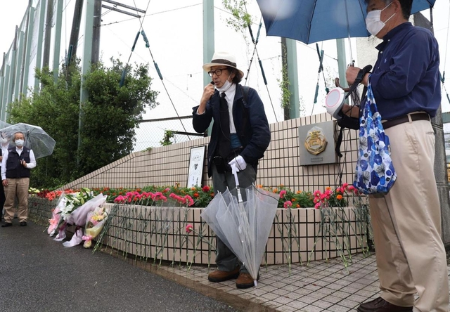 校門前に花を供え、追悼の言葉を述べる参加者＝６日午前、神戸市西区美賀多台９、神戸高塚高校（撮影・吉田敦史）