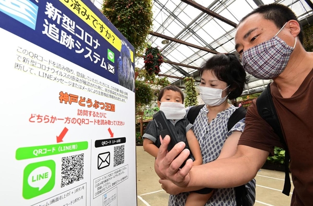 新型コロナ追跡システムに登録するため、園内の「ＱＲコード」にスマートフォンをかざす家族連れ＝神戸市中央区港島南町７、神戸どうぶつ王国（撮影・秋山亮太）