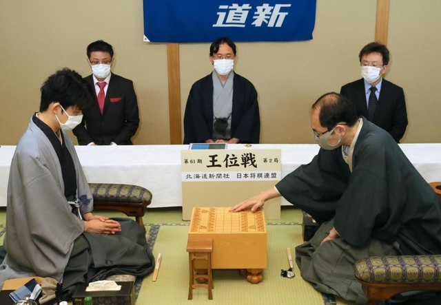 王位戦第２局で初手を指す木村一基王位（右）。左は藤井聡太七段＝１３日午前、札幌市、ホテルエミシア札幌