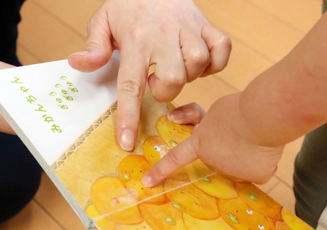 絵本の読み聞かせ。心を寄せ合うほど、保育士と子どもの距離が近づく＝神戸市内