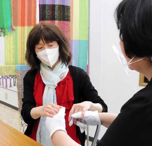 触手話で意思を伝える盲ろう者の女性。介助員もフェースシールドで感染を予防する＝神戸市内