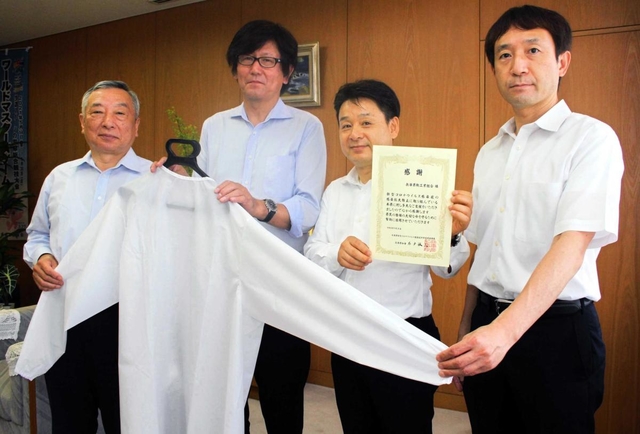 荒木一聡副知事（左）に医療用ガウンを手渡す兵庫県鞄工業組合の由利昇三郎理事長（左から２人目）ら＝兵庫県庁