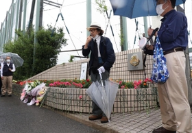 校門前に花を供え、追悼の言葉を述べる参加者＝６日午前、神戸市西区美賀多台９、神戸高塚高校（撮影・吉田敦史）