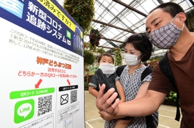 新型コロナ追跡システムに登録するため、園内の「ＱＲコード」にスマートフォンをかざす家族連れ＝神戸市中央区港島南町７、神戸どうぶつ王国（撮影・秋山亮太）