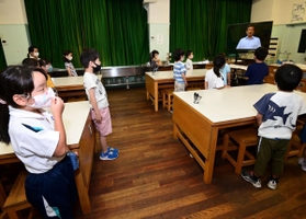 テレビを使った終業式で、校長の話を聞く神戸市立宮本小学校の児童たち＝２２日午前、神戸市中央区宮本通２（撮影・秋山亮太）