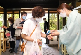 入り口で手指をアルコール消毒し、検温に応じる宿泊客ら＝２２日午後、神戸市北区有馬町、欽山（撮影・吉田敦史）