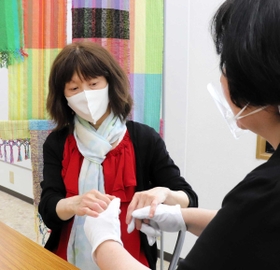 触手話で意思を伝える盲ろう者の女性。介助員もフェースシールドで感染を予防する＝神戸市内