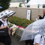 校門前に花を供え、追悼の言葉を述べる参加者＝６日午前、神戸市西区美賀多台９、神戸高塚高校（撮影・吉田敦史）