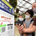 新型コロナ追跡システムに登録するため、園内の「ＱＲコード」にスマートフォンをかざす家族連れ＝神戸市中央区港島南町７、神戸どうぶつ王国（撮影・秋山亮太）