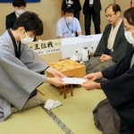 封じ手が入った封筒を立会人の深浦康市九段（右）に手渡す藤井聡太七段。右から２人目は木村一基王位＝１３日午後、ホテルエミシア札幌