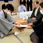 封じ手が入った封筒を立会人の深浦康市九段（右）に手渡す藤井聡太七段。右から２人目は木村一基王位＝１３日午後、ホテルエミシア札幌