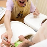 子どもに離乳食を食べさせる院内保育所の保育士。笑顔でそしゃくをする様子を見せると食べさせやすく、マスクは外す＝神戸市内