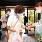 入り口で手指をアルコール消毒し、検温に応じる宿泊客ら＝２２日午後、神戸市北区有馬町、欽山（撮影・吉田敦史）