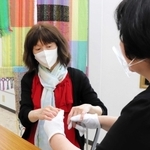 触手話で意思を伝える盲ろう者の女性。介助員もフェースシールドで感染を予防する＝神戸市内