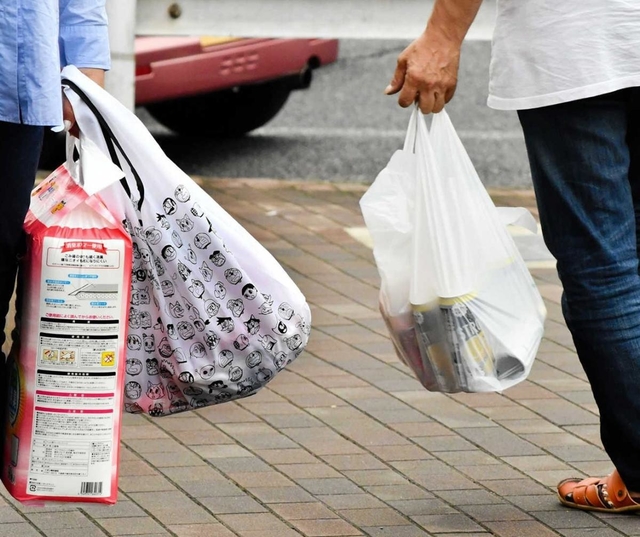 スーパーの前では買い物客が、有料となったプラスチック製レジ袋とエコバッグを提げて行き交う＝神戸市内