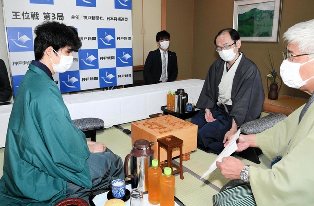 立会人の淡路仁茂九段から封じ手を示される藤井聡太棋聖（左）。奥は木村一基王位＝５日午前、神戸市北区有馬町、旅館「中の坊瑞苑」（撮影・後藤亮平）