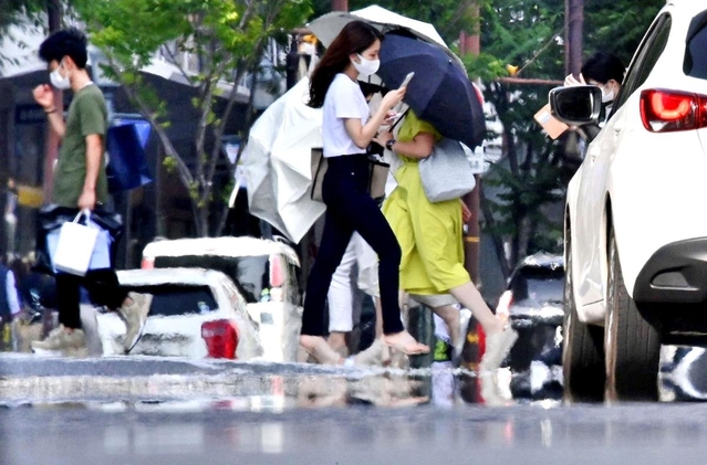 街中の路上に現れた蜃気楼の一種「逃げ水」。道行く人の足元が揺らいで見えた＝６日午後、神戸市中央区