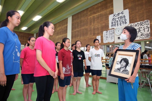 部室に飾ってある溝端令子さんの写真を手に、生徒たちへ日航機墜落事故や創作ダンス部の成り立ちについて話す山中寿美教諭（右）＝西宮市枝川町、武庫川女子大付属中・高校（撮影・風斗雅博）