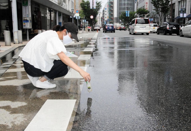 散水車が通った後の路面温度の変化を記録する神戸大大学院生＝神戸市中央区三宮町１