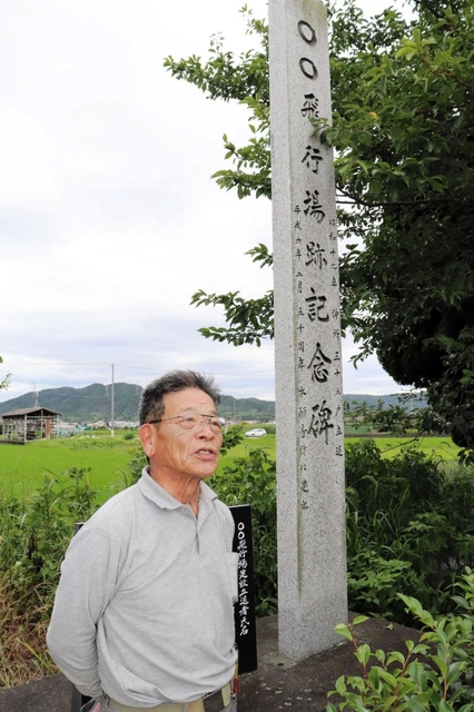 「○○飛行場跡記念碑」の前に立つ佐藤繁俊さん。「○○」は今も、飛行場跡地の集落を指す言葉として使われるという＝南あわじ市松帆脇田甲