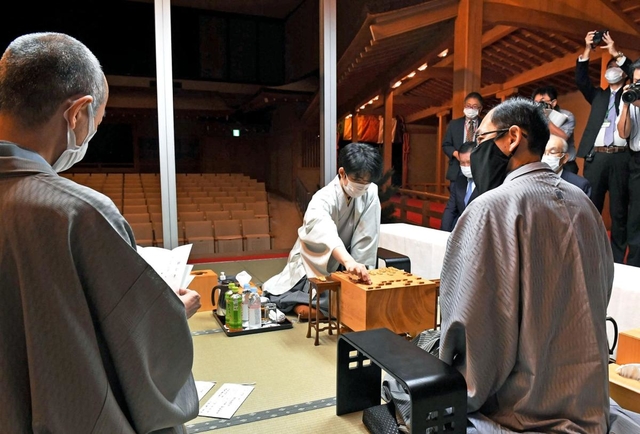 王位戦第４局で立会人の中田功八段（左）が読み上げた封じ手を指す藤井聡太棋聖（中央）。右は木村一基王位＝２０日午前９時２分、福岡市中央区の大濠公園能楽堂（撮影・穴井友梨）