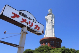 解体撤去が決まった「世界平和大観音像」の足元に並び立つ「アメリカ」の看板＝淡路市釜口