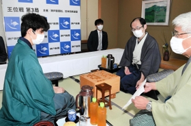 立会人の淡路仁茂九段から封じ手を示される藤井聡太棋聖（左）。奥は木村一基王位＝５日午前、神戸市北区有馬町、旅館「中の坊瑞苑」（撮影・後藤亮平）