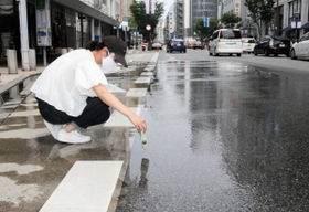 散水車が通った後の路面温度の変化を記録する神戸大大学院生＝神戸市中央区三宮町１