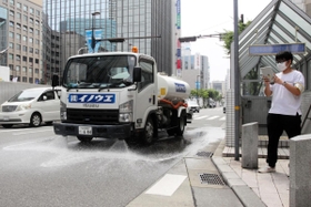 路面を冷やすため、水をまきながら走る散水車。右は温度の変化を記録する神戸大の学生＝神戸市中央区三宮町１
