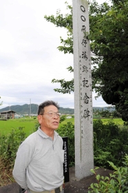 「○○飛行場跡記念碑」の前に立つ佐藤繁俊さん。「○○」は今も、飛行場跡地の集落を指す言葉として使われるという＝南あわじ市松帆脇田甲