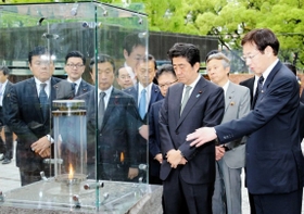 久元喜造・神戸市長（右）から「１・１７希望の灯り」について説明を受ける安倍晋三首相（右から３人目）＝２０１５年５月、神戸市中央区の東遊園地（代表撮影）