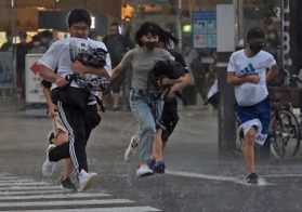突然降り出した激しい雨の中、走って交差点を渡る人ら＝３０日午後５時４８分、神戸市中央区東川崎町１（撮影・後藤亮平）