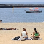 海水浴が中止され「遊泳自粛」の須磨海岸で日光浴などをする人たち＝１日午前、神戸市須磨区（撮影・斎藤雅志）