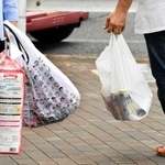 スーパーの前では買い物客が、有料となったプラスチック製レジ袋とエコバッグを提げて行き交う＝神戸市内