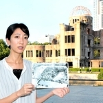 ピースボランティアの松本愛美さん。「平和記念公園は、昔は中島地区という住宅街だった」と写真を持って説明する＝広島市中区中島町、平和記念公園