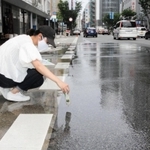 散水車が通った後の路面温度の変化を記録する神戸大大学院生＝神戸市中央区三宮町１