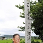 「○○飛行場跡記念碑」の前に立つ佐藤繁俊さん。「○○」は今も、飛行場跡地の集落を指す言葉として使われるという＝南あわじ市松帆脇田甲