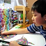 首里城再建への思いを込め、絵画を制作した柳生君。机の上にはコピックが並ぶ＝西宮市内