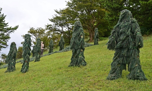 自然の風景に紛れ込む軍用品のギリースーツを使った作品＝１１日午前、神戸市灘区六甲山町
