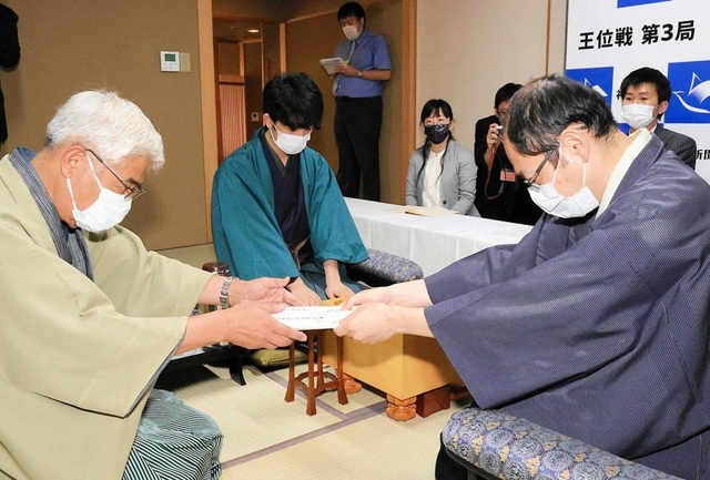 立会人の淡路仁茂九段に封じ手が入った封筒を渡す木村一基王位（右）＝８月４日午後、神戸市北区有馬町、「中の坊瑞苑」