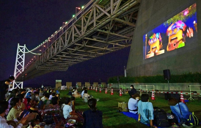明石海峡大橋の橋台に映し出されたスクリーンで映画を楽しむ家族連れら＝２０日夜、神戸市垂水区東舞子町（撮影・秋山亮太）