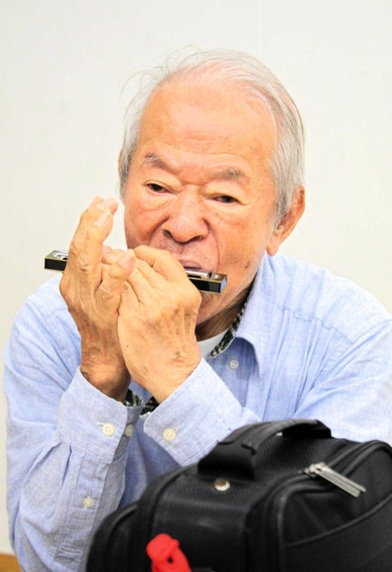 戦中に小学校の先生の家で教えてもらったハーモニカを吹く田間貞雄さん＝西宮市浜脇町、浜脇小学校
