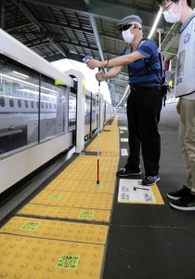 点字ブロック上のＱＲコードを読み取って駅構内を移動する視覚障害者＝ＪＲ新神戸駅