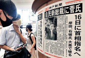 新総裁選出を伝える号外に足を止める人たち＝１４日午後、ＪＲ神戸駅（撮影・鈴木雅之）