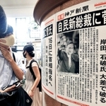 新総裁選出を伝える号外に足を止める人たち＝１４日午後、ＪＲ神戸駅（撮影・鈴木雅之）