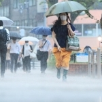 雨脚が強まる中、足元を気にしながら歩く人ら＝２５日午前、神戸市中央区相生町３