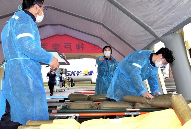 新型コロナ対策で人形を負傷者に見立て、自身も防護服を着用して訓練に参加する医療関係者ら＝１９日午後、神戸空港（撮影・中西幸大）
