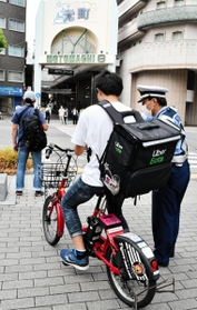 食事宅配サービス配達員に、交通ルールを守るよう呼び掛ける警察官＝神戸市中央区