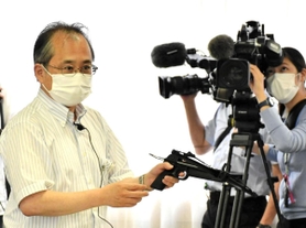 条例案の有識者検討会で実物のボーガンを手に説明する県の担当者＝７月、神戸市中央区